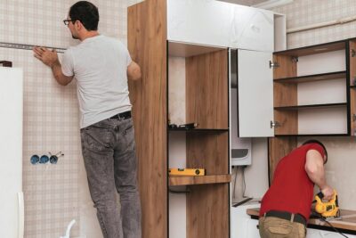 two-craftsmen-furniture-makers-assemblers-are-installing-modern-kitchen-home_537579-2549